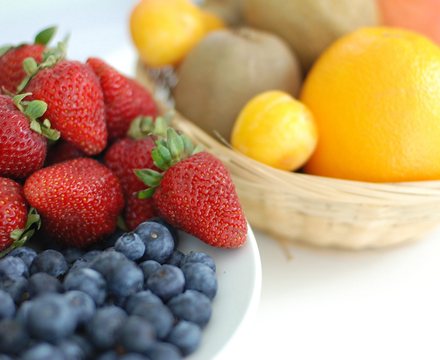 A bowl of fresh strawberries, blueberries, kiwi and citrus fruit