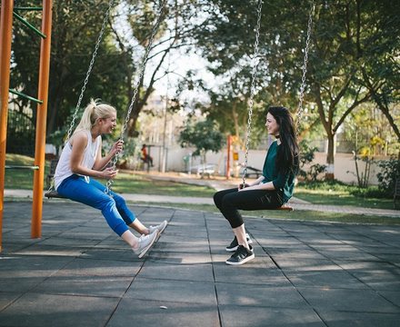 Friends relaxing on swings in a sunny park